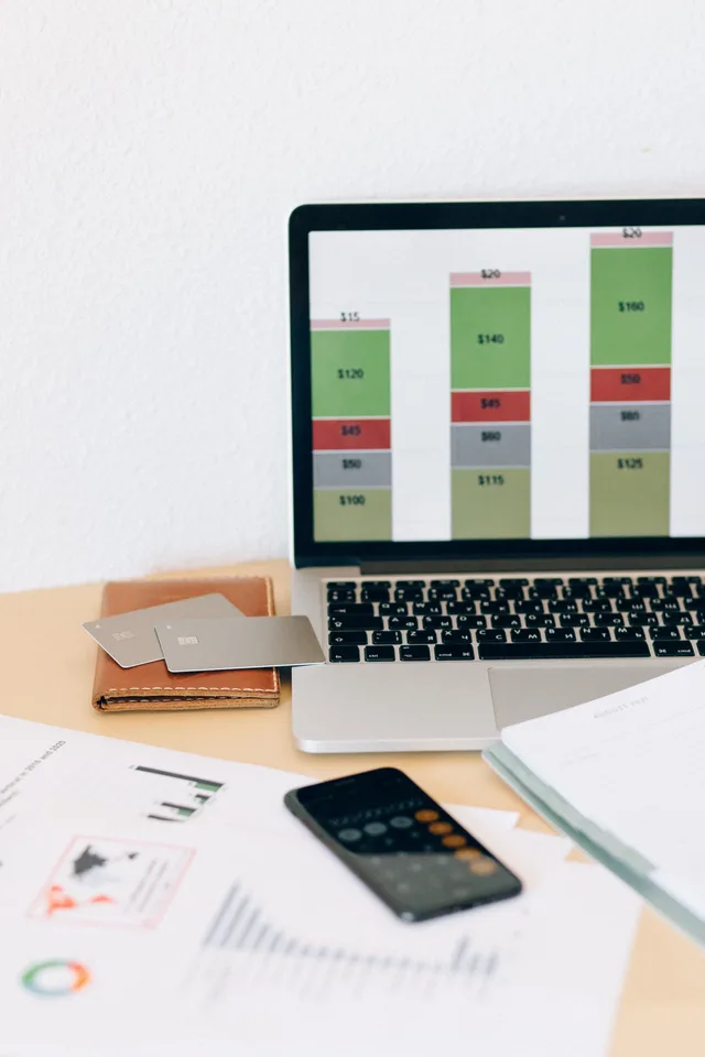 Laptop displaying financial chart alongside documents and credit cards on desk. Comparer les logiciels de gestion : critères objectifs pour PME en Suisse