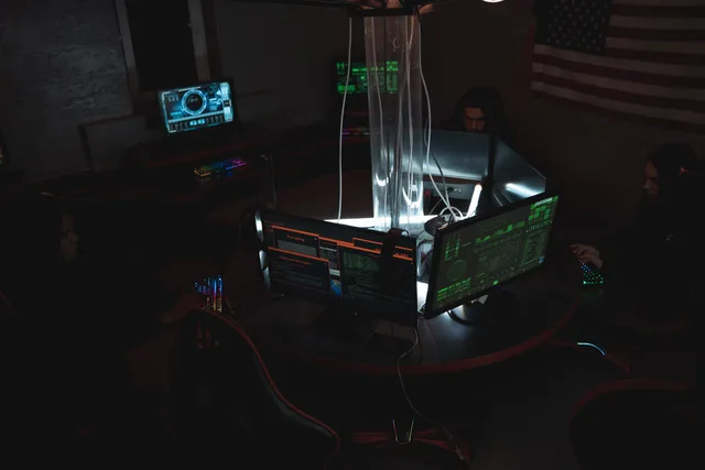 Team of cybersecurity experts collaboratively working on data protection in a dimly lit room filled with computers. Déclarer une cyberattaque en Suisse : procédure et délais